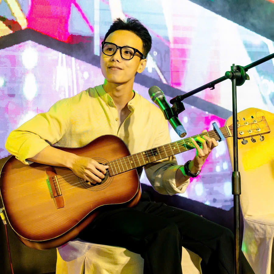 Trần Minh Đức ôm đàn guitar thùng trên sân khấu
